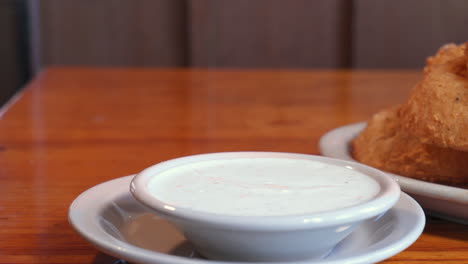 Caucasian-hand-picks-up-large-deep-fried-onion-ring-dips-into-sauce,-slider-slow-motion-HD