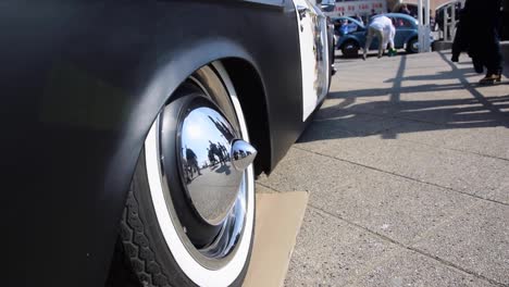 people reflexion on shining car rims of a vintage car