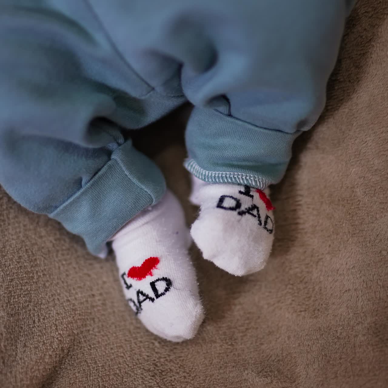 Adorable babe's feet in tiny socks. I love you dad socks on the little feet on the grey backdrop. Close up