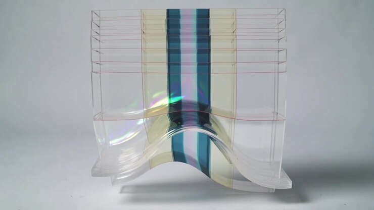 Bending clear film on acrylic holder at tabletop, arching and refracting central teal strip