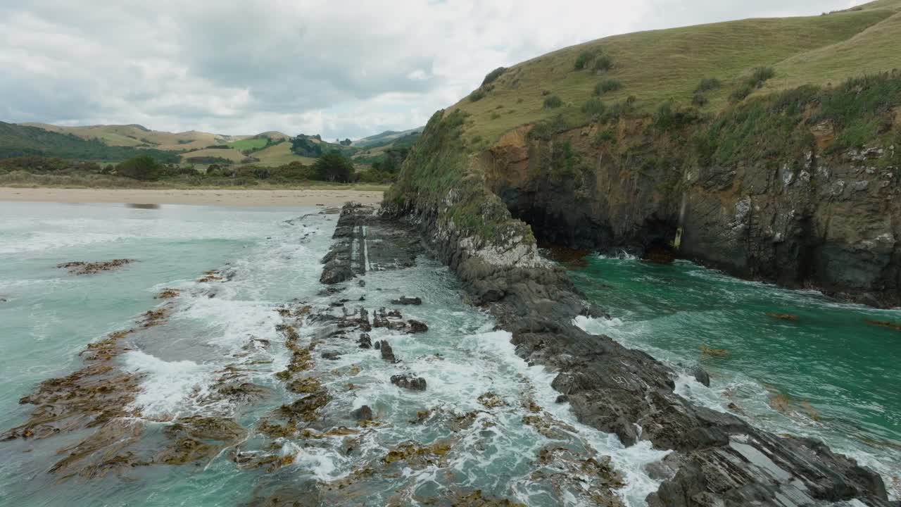 Aerial drone view of waves breaking on rugged and rocky coastline covered with kelp and seaweed on the remote Cannibal Bay, Catlins, South Island of New Zealand Aotearoa