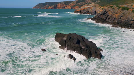 stormy sea water splashing on coastal rocks sunny day. drone rocky coastline