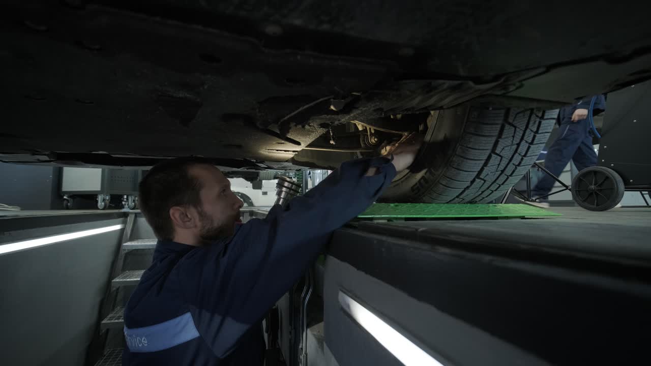 mecánico inspeccionando el tren de aterrizaje del automóvil en el pozo de servicio