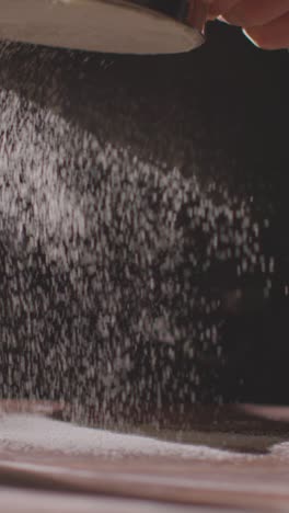 vertical video overhead shot of flour being sieved onto work surface for baking