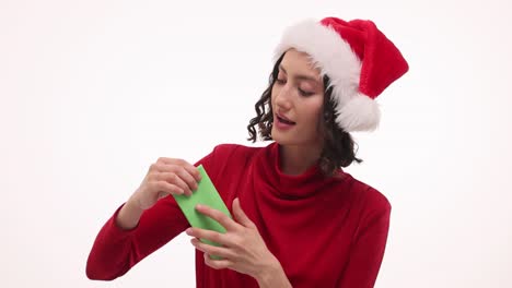 woman in santa hat opening a small green gift
