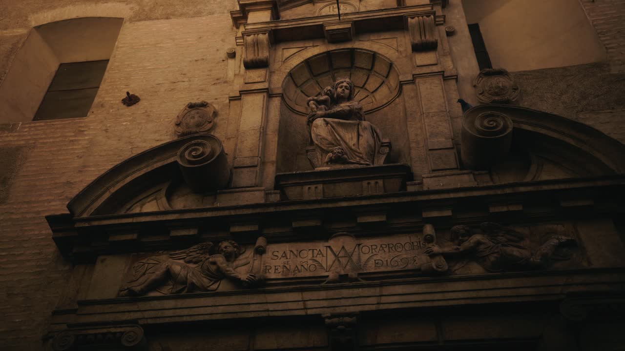 Ozdobny kamienny relief z posągiem wbudowanym w historyczną fasadę.