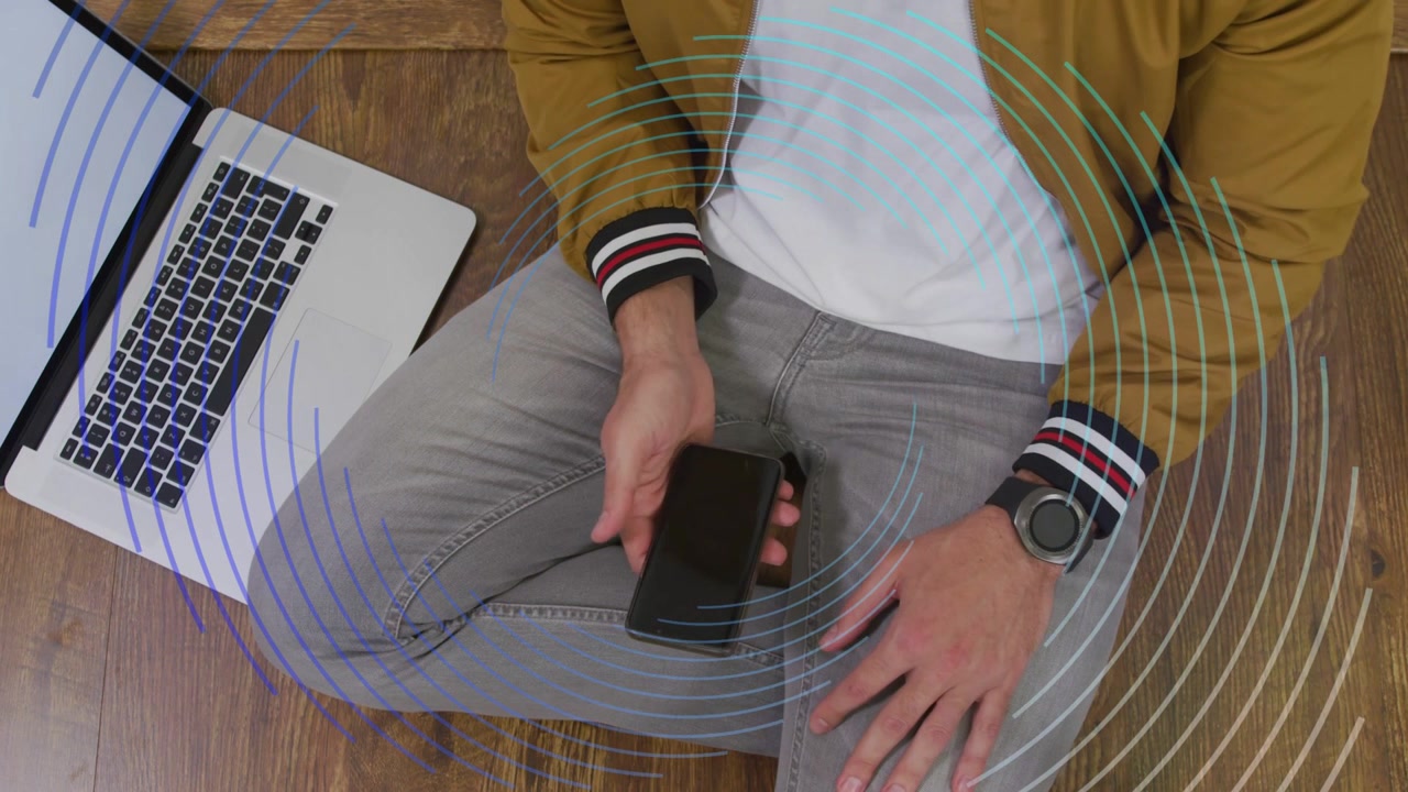 Uomo che regola il telefono, toccando accanto al laptop, attivando gli anelli, posizionandolo sulla coscia destra per una demo tecnologica