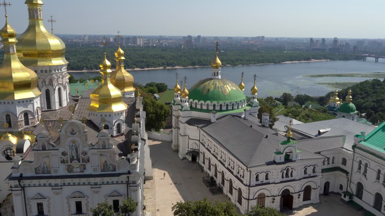 Ukraine,Kyiv,Pechersk Lavra,Drone footage, close up of Lavra's main buildings,towers, golden domes on a sunny day. Dnipro river, bridge, parks and city lies behind the beautiful historical buildings.