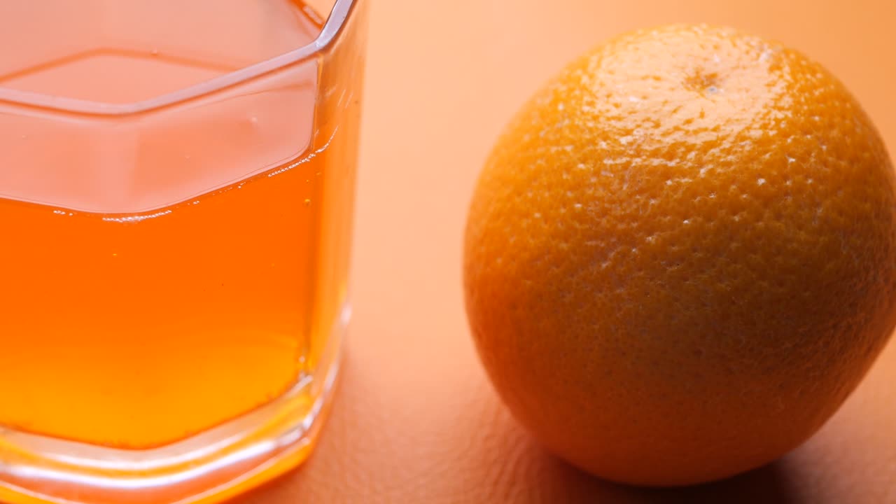 Appelsinjuice i glass og frukt i en skål på bordet