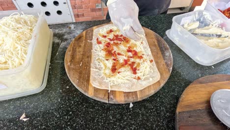 preparing a pizza with toppings on wooden board.