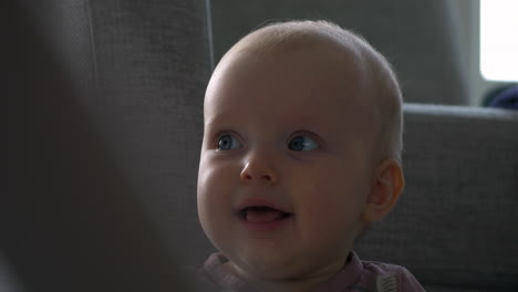 closeup of a happy blue-eyed baby girl sitting up