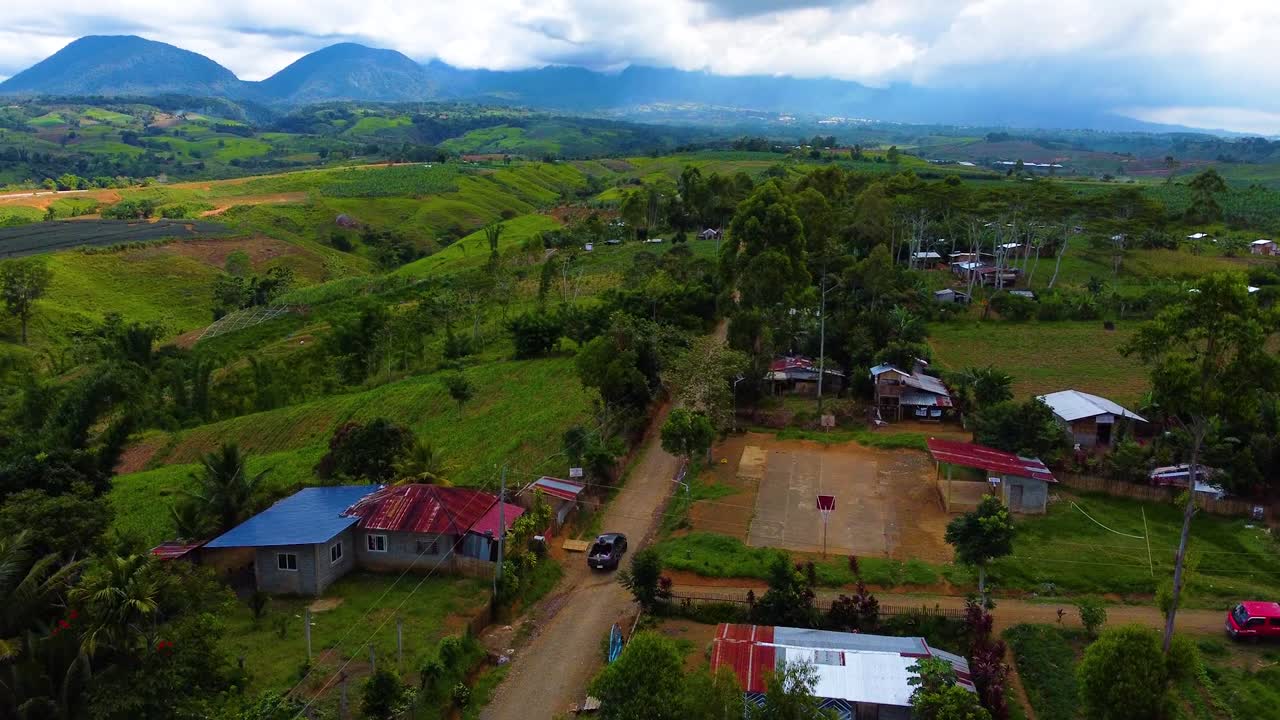 toma aérea de camiones que se dirigen a una montaña que pasa por un pueblo