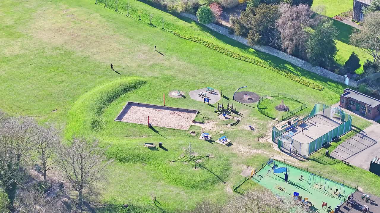 Aerial overview of Elsecar park and open grassland play areas site with stone buildings and adjacent grassland