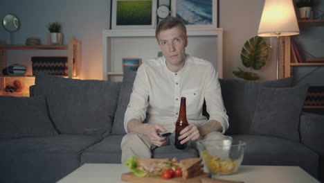 man relaxing at home with snacks and drinks, watching tv