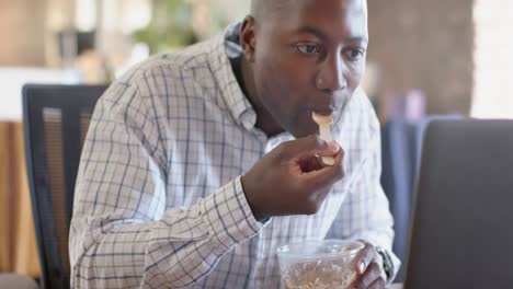 Happy-african-american-casual-businessman-using-smartphone-and-having-lunch-in-office,-slow-motion