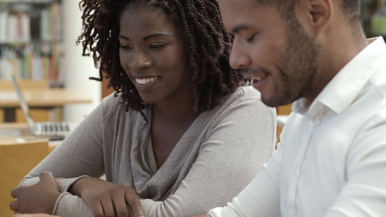 Colleagues sitting at library and using laptop