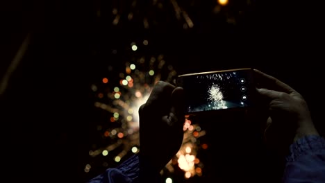 silhouette of a man photographing fireworks at night sky. beautiful salute in honor of the holiday
