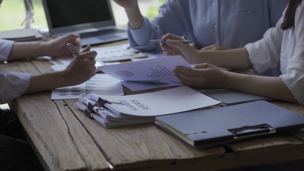 Close-up of a financial analyst and a planning team of young entrepreneurs discussing project ideas using papers to brainstorm modern business firms.