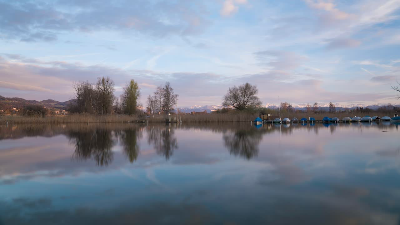 hermosa puesta de sol en un lago con montañas en el fondo y barcos en el lago
