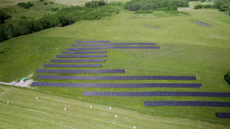 Descending-aerial-shot-of-countryside-field-and-farm-of-solar-panel-units-during-sunlight