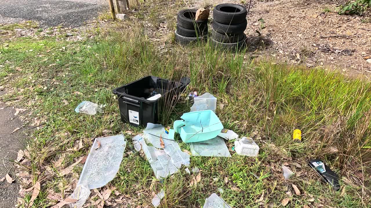 Discarded trash and debris scattered near a rural road, highlighting environmental neglect and pollution issues