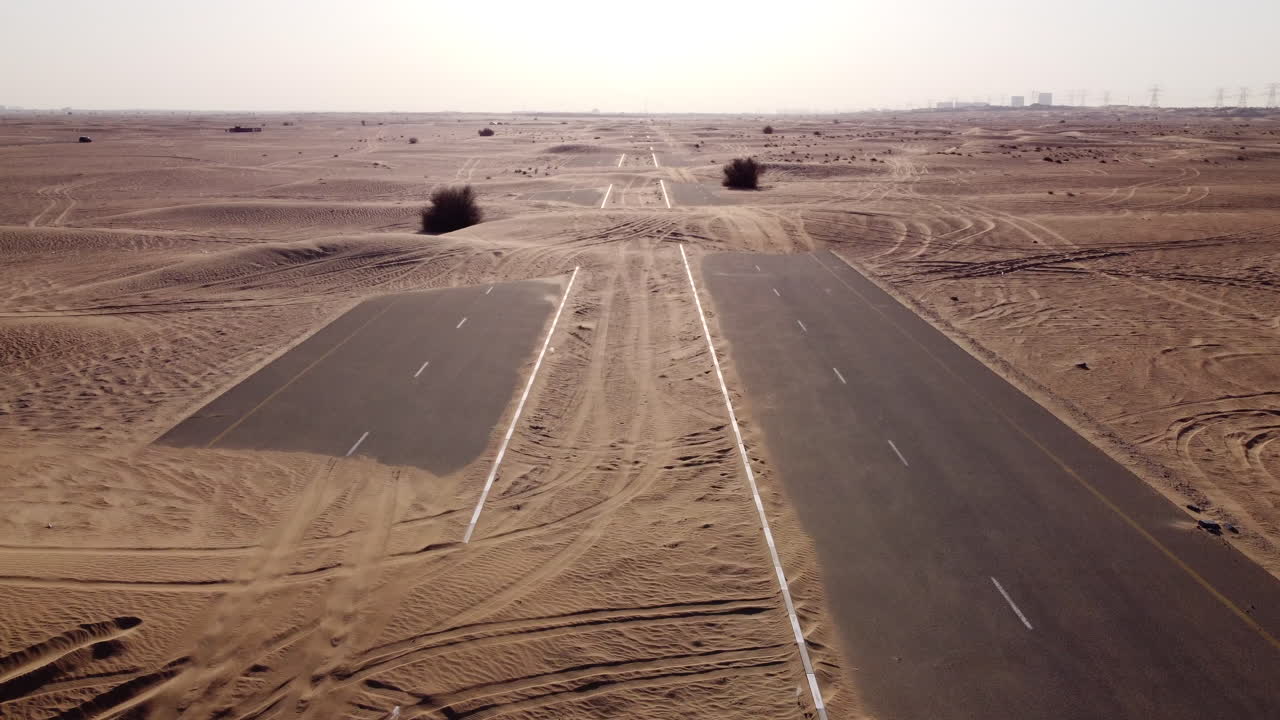 화창한 날 아스팔트에 모래가 깔린 황량한 도로 위로 공중 비행