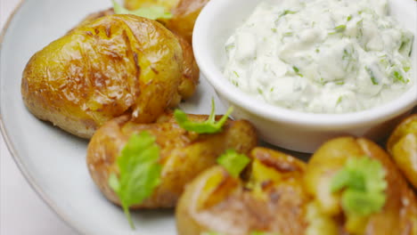 rotating white plate with roasted potatoes and dip