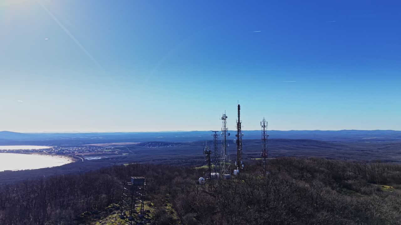 Communication towers stand on a mountain under clear sky in daytime