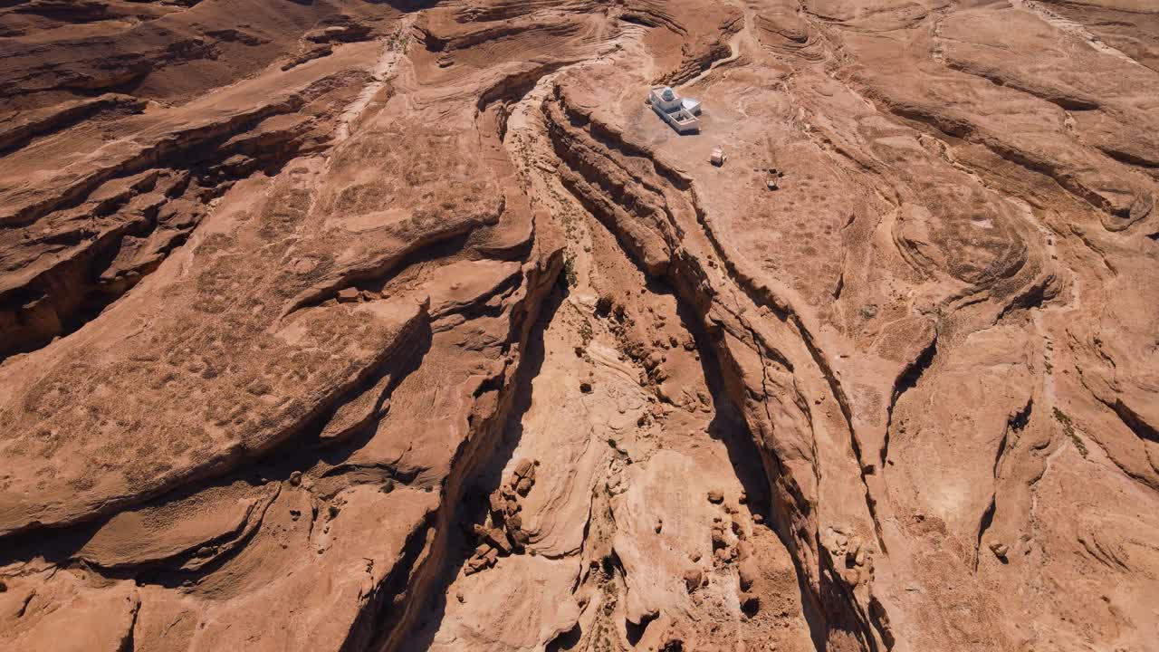 A red rock formation with a small tunnel in it, surrounded by orange cliffs and rocks.