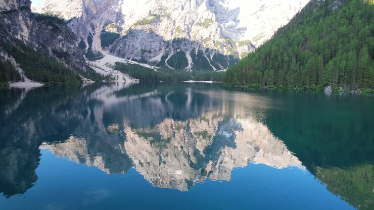 Volo aereo a bassa quota sul Pragser Wildsee, con il Seekofel che si riflette sulla superficie dell'acqua.