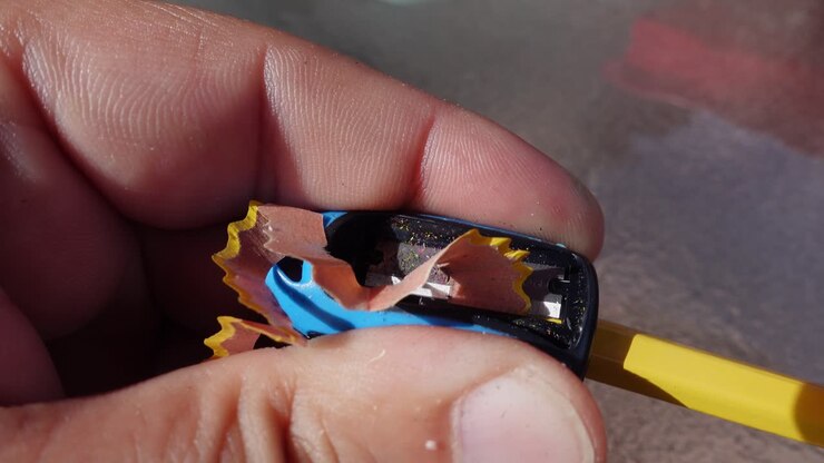 Close up of hand holding a blue pencil sharpener being used