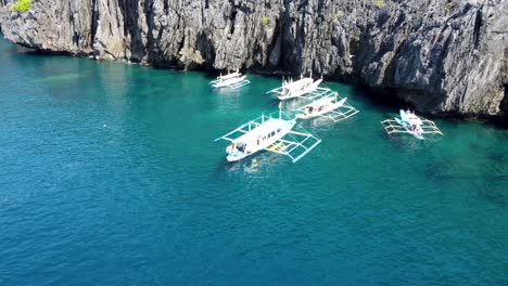 Traditional-Filipino-bangka-outrigger-Tour-Boats-at-secret-beach,-El-Nido-Philippines