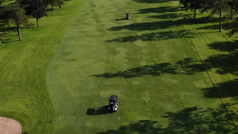 Passengers-on-Golf-Cart-Traveling-Down-Course-During-Summertime,-Tracking-Shot