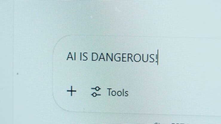 A bold statement appears on screen as a user types “AI IS DANGEROUS!” into a chat window, highlighting concerns about artificial intelligence and ethical risks