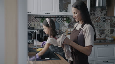 mother and daughter washing dishes in kitchen