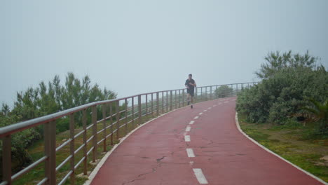 motivated athlete running morning track. muscular fit man jogging doing cardio