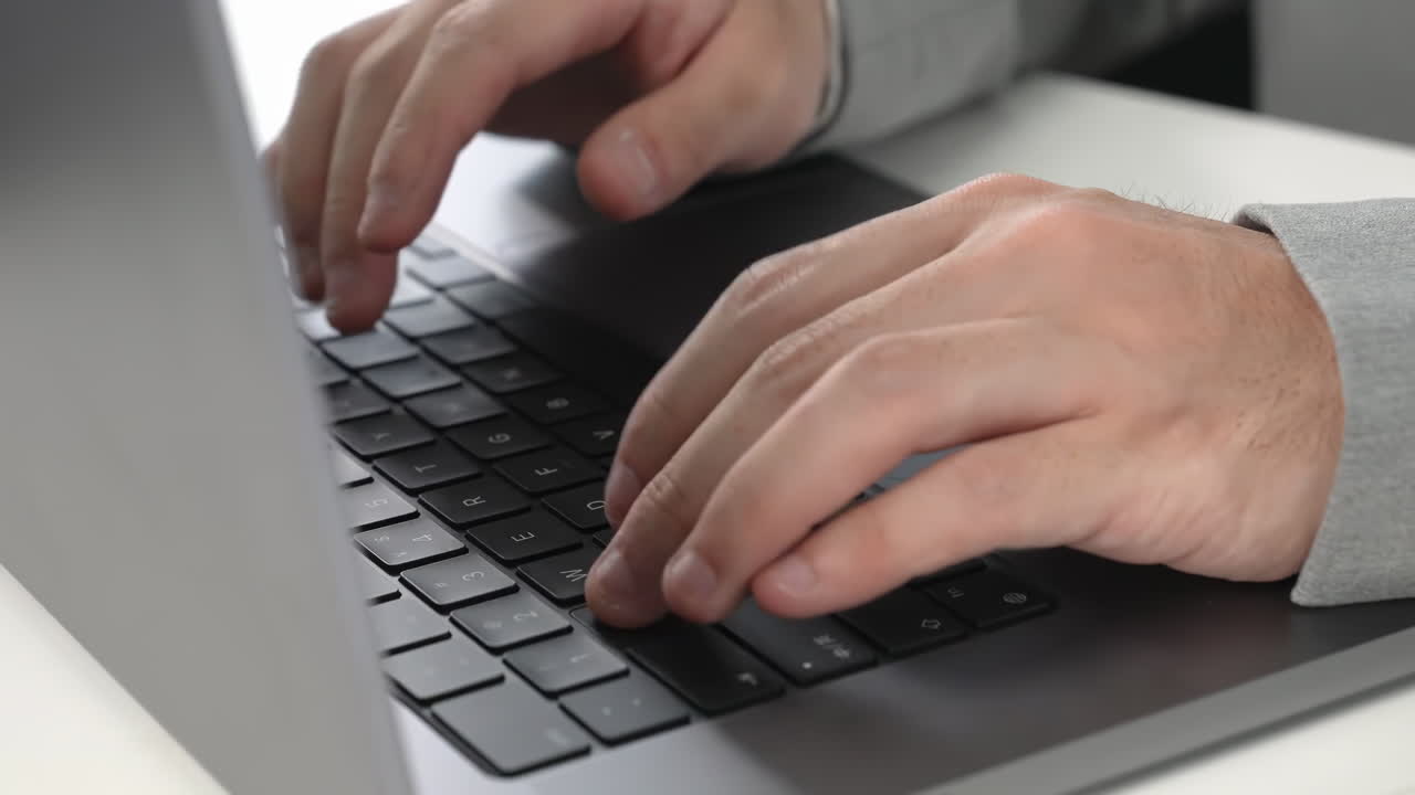 Mani di un uomo d'affari irriconoscibile che digitano su una tastiera di un computer portatile a una scrivania in un ufficio. Lavoro digitale, codifica, inserimento dati o servizio clienti. Tecnologia, cybersecurity, turni di notte.