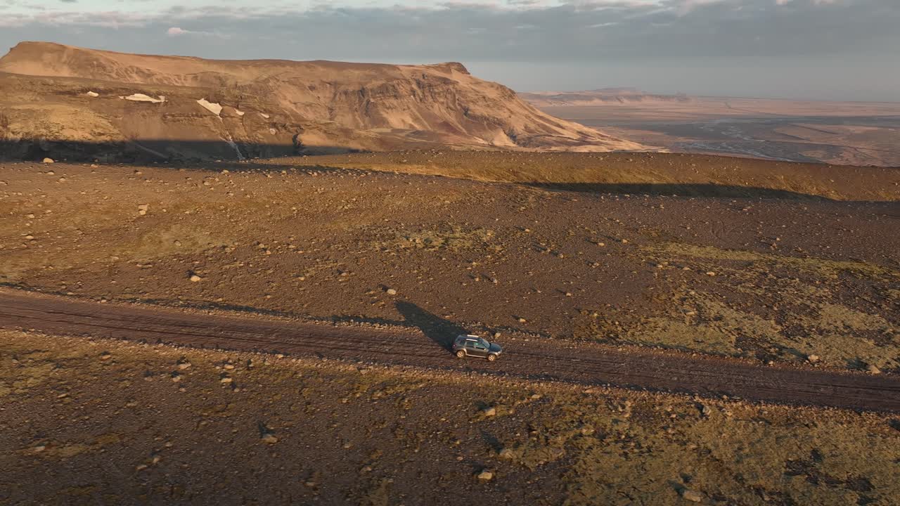tomada de un avión no tripulado de un vehículo todoterreno que viaja a través del vasto paisaje rocoso de las tierras altas de islandia, rodeado de montañas y desierto abierto