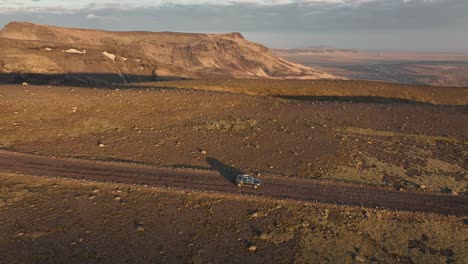 drone shot of an off-road vehicle traveling through the vast, rocky landscape of icelandic highlands, surrounded by mountains and open wilderness