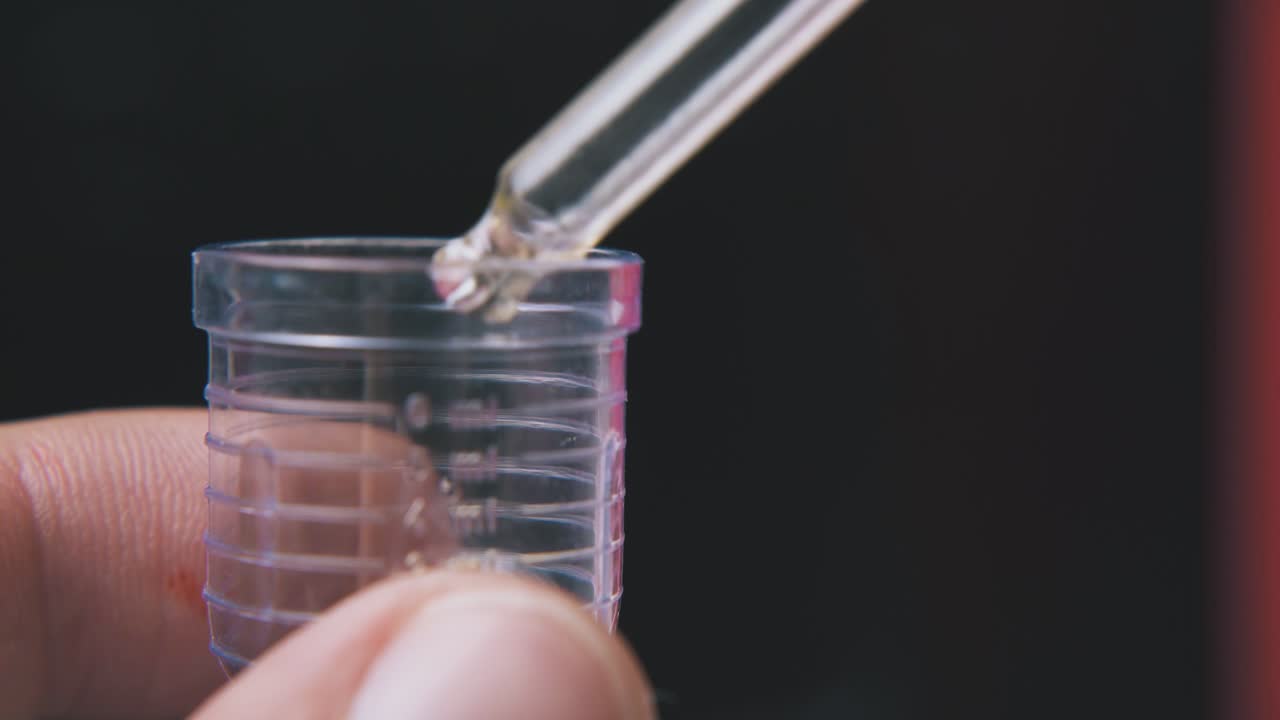 조수 는 검은색 배경 에 있는 컵 에 갈색 물 을 떨어뜨린다