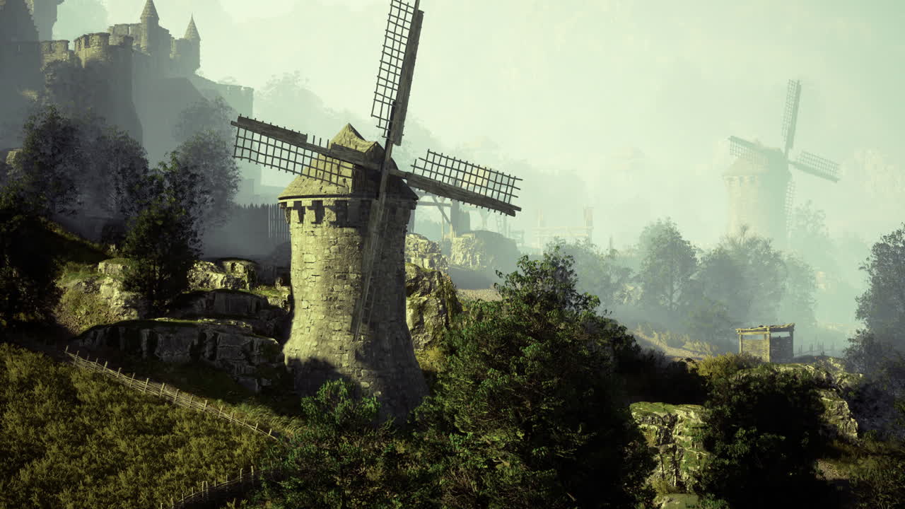 Windmills and ancient castle in misty hillside landscape at dawn