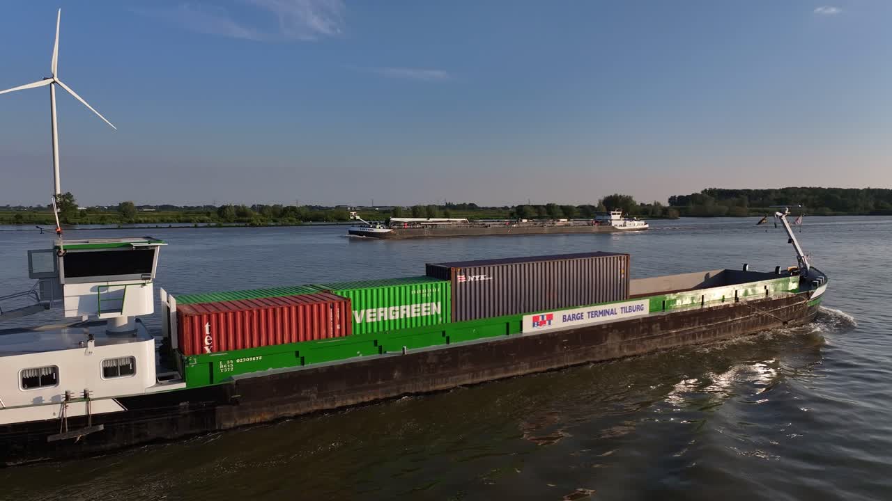 Dutch container ship Tornado moves on river by wind turbine, aerial