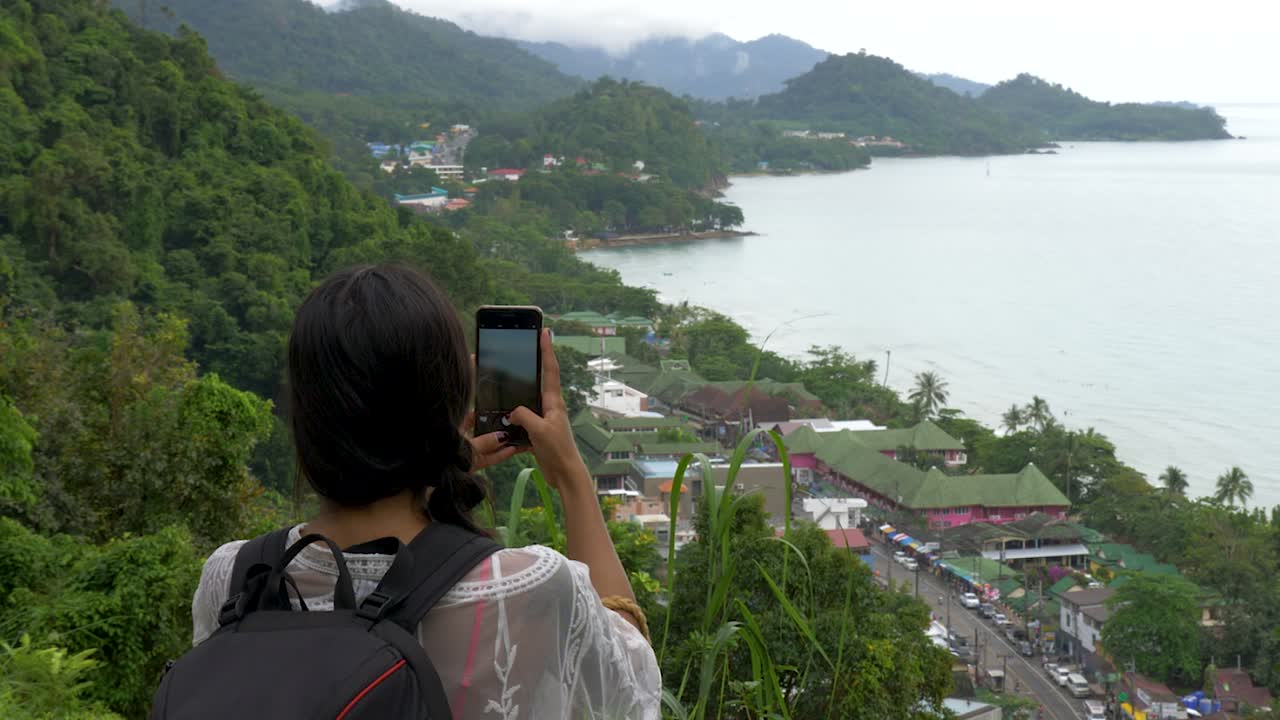 Gadis di titik pandang sedang mengambil gambar dengan ponselnya di Koh Chang, Thailand