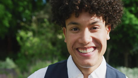retrato de un hombre biracial feliz en un día soleado en una boda.