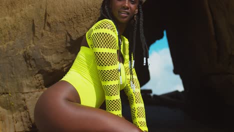 sexy dark skin girl at the entrance to a cave in a sexy thong bikini