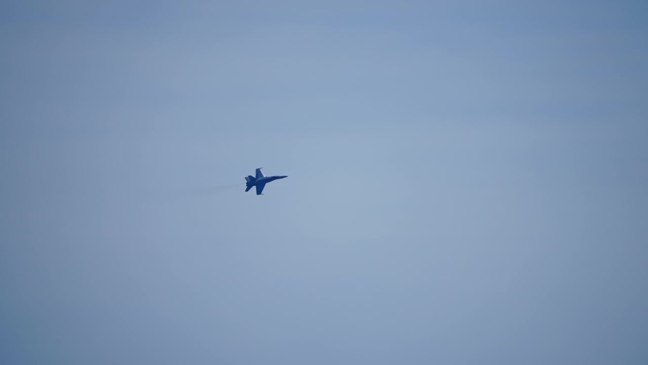Tweemotorige militaire straaljager maakt een bocht in een grijsblauwe lucht