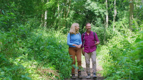 mature couple in countryside hiking along path through forest together