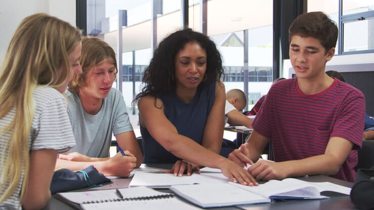 Teacher studying school books in class with high school kids