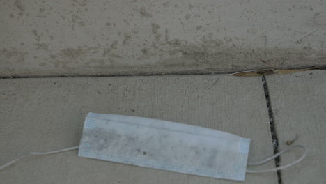 A-dirty-and-used-disposable-face-mask-is-dropped-to-the-sidewalk