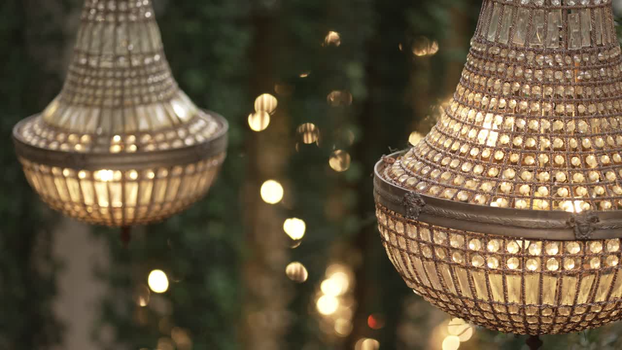 crystal chandeliers hanging with warm lights and blurred bokeh glow in romantic garden